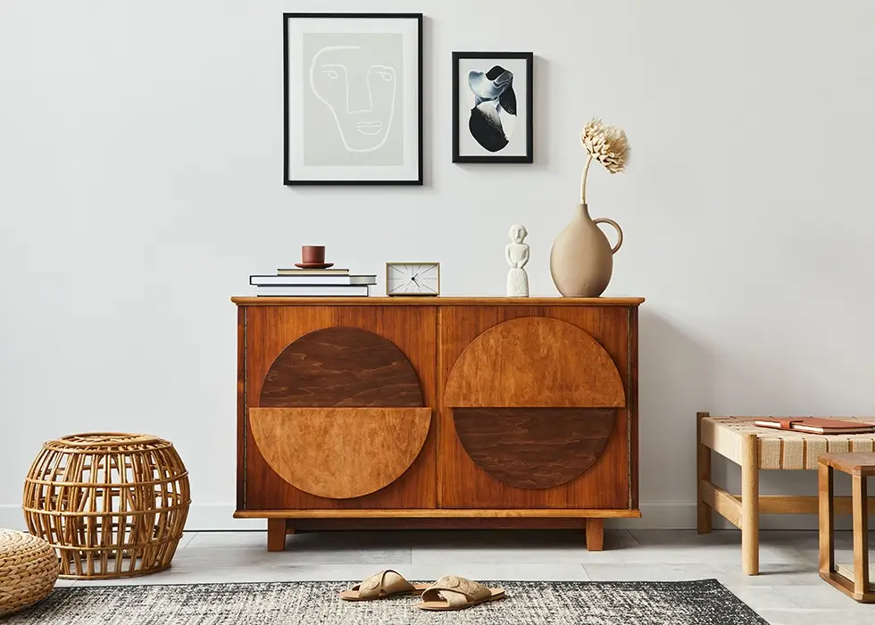 Stilvolle skandinavische Wohnzimmerkomposition Stilvolle skandinavische Wohnzimmerkomposition mit Design-Kommode, schwarzen Posterrahmen-Attrappen, Rattan-Pouf, Uhr, Holzhocker, Buch, Dekoration und persönlichen Accessoires in moderner Wohnkultur.